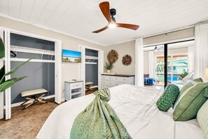 A bedroom with a bed, a ceiling fan, a walk-in closet, and a view of the outdoors.