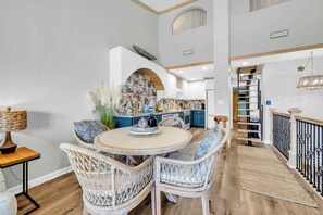 A dining area with wicker furniture, a kitchen in the background, and a staircase. - Seahab *Waterfront Dock* Private Beach Access! (Destin)