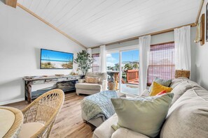 A spacious living room with a large window, a sofa, a chair, and a desk with a painting. - Seahab *Waterfront Dock* Private Beach Access! (Destin)