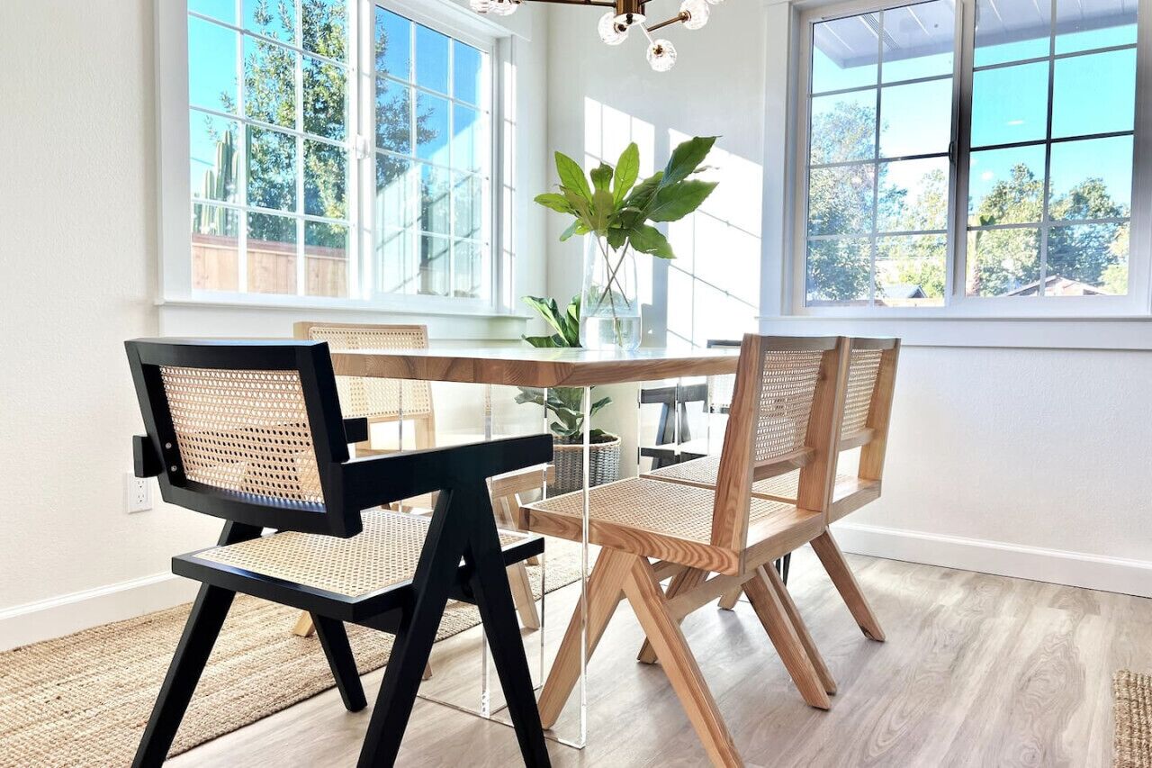 Un coin repas avec une table en verre, des chaises noires et en bois, et une plante en pot.