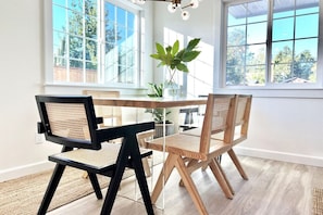 Un comedor con mesa de vidrio, sillas negras y de madera, y una planta en maceta.