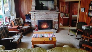 A cozy living room with a fireplace, a television mounted above it, and comfortable seating. - Sandy Pines Cottage. Lake Muskoka, Gravenhurst (Gravenhurst)