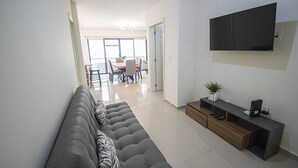 Un salon moderne avec un canapé gris, un meuble de rangement en bois et un téléviseur à écran plat fixé au mur.