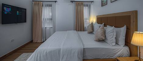 Un dormitorio con cama, una mesita de noche con lámpara, aire acondicionado de pared y televisor en la pared.