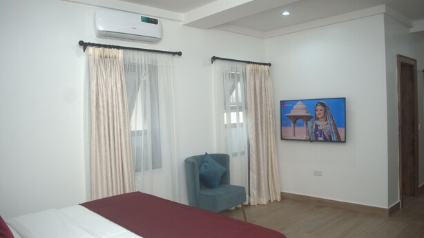 Habitación de hotel con cama, una silla, televisor y aire acondicionado.