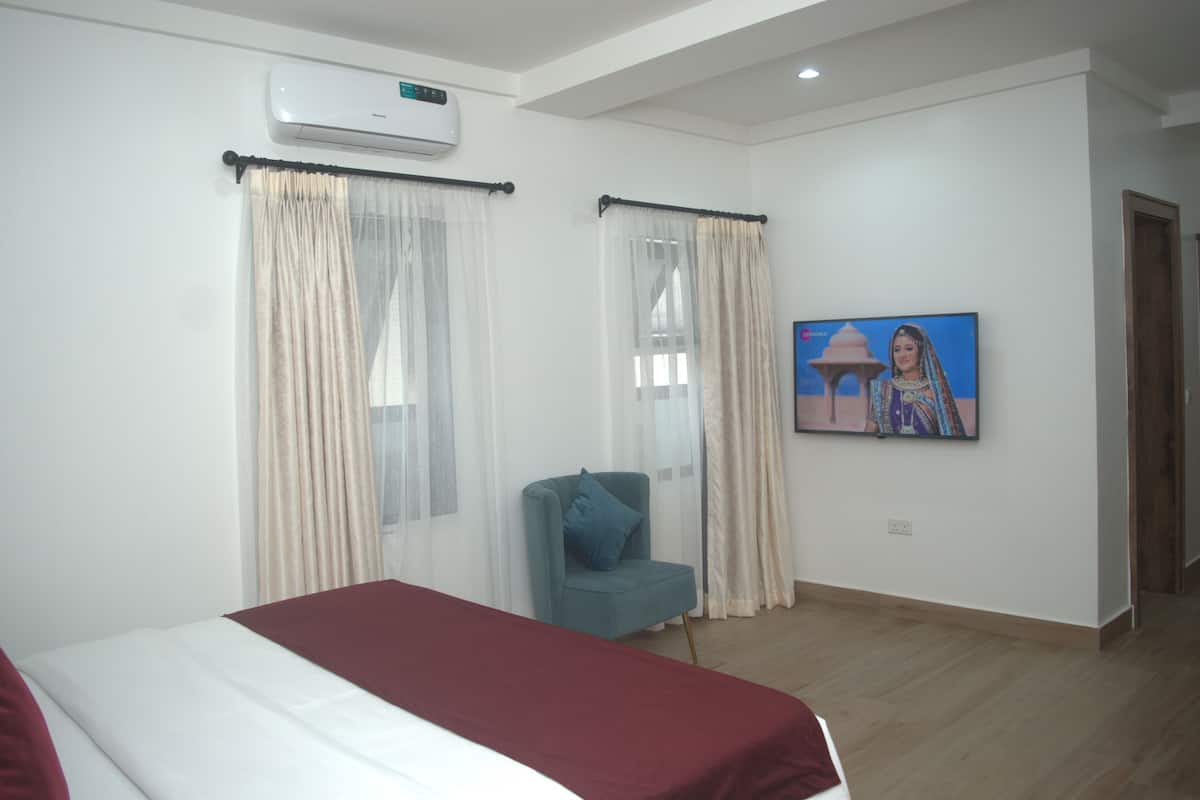 Habitación de hotel con cama, una silla, televisor y aire acondicionado.