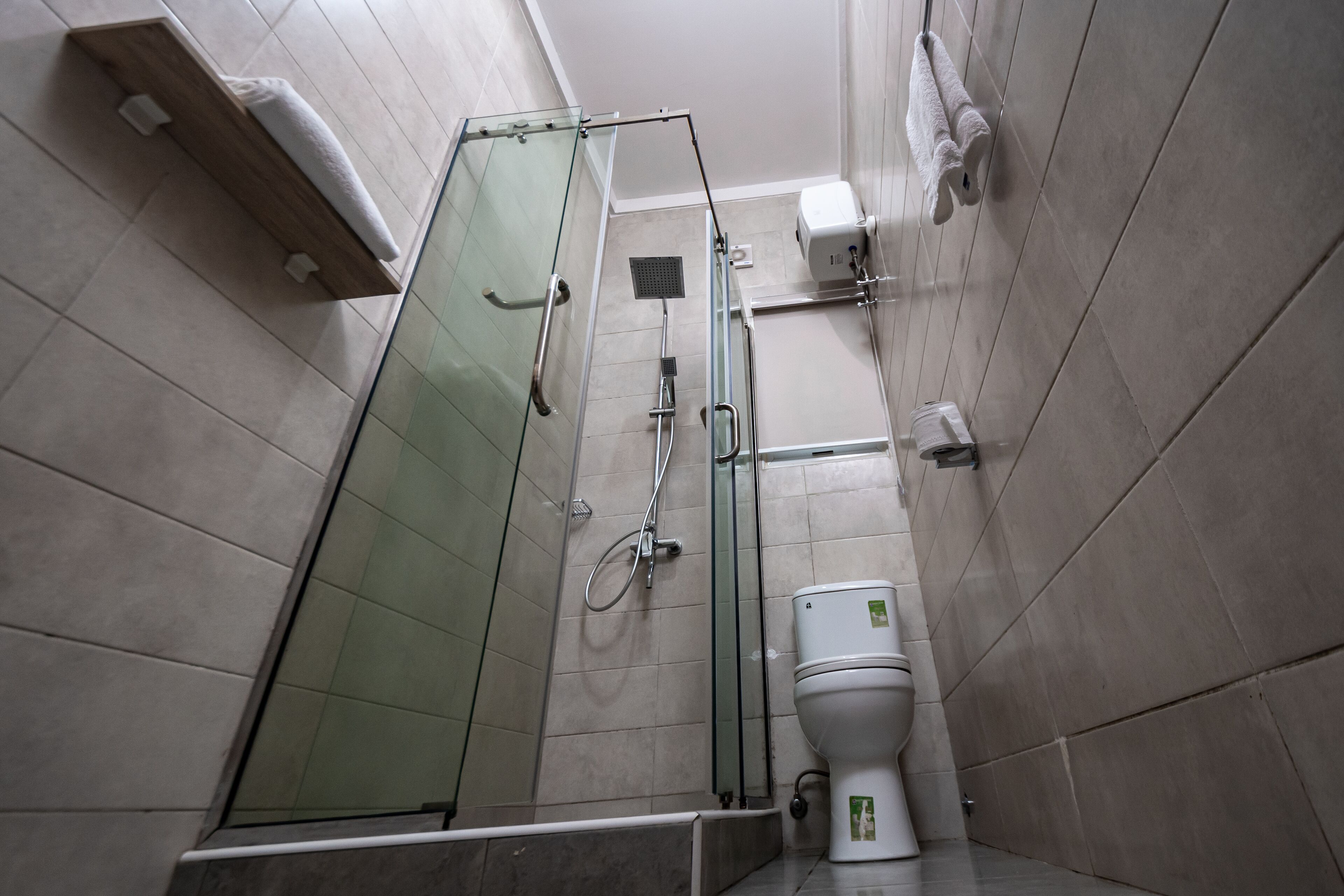 Un baño moderno con ducha envuelta en vidrio, inodoro y barra para toallas.