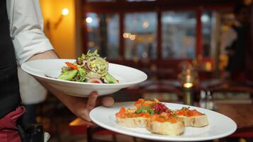 Une personne tenant deux assiettes, l’une contenant une salade et l’autre des amuse-gueules.
