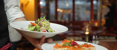 A person holding two plates, one with a salad and the other with appetizers.