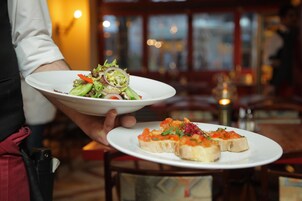 Una persona sosteniendo dos platos, uno con una ensalada y el otro con aperitivos.