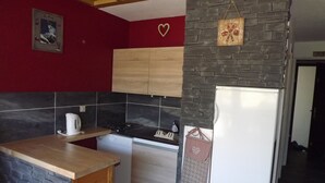 Een kleine keuken met een houten aanrecht, een fornuis, een vaatwasser en een koelkast.