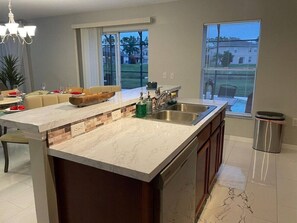 A modern kitchen with a marble countertop, a built-in sink, and a view of the outdoors.