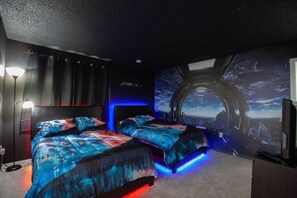 Un dormitorio con dos camas, un ventanal amplio y un mural con temática espacial.