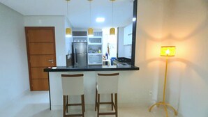 Una cocina con encimera negra, dos taburetes de bar, un microondas y una estufa.