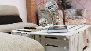 A living room with a sofa, a coffee table with books and a remote control, and decorative glass spheres. - Casa Dahlia Queretaro (Querétaro)