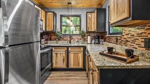 Una cocina moderna con electrodomésticos de acero inoxidable, armarios de madera y encimera de granito.