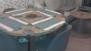 Ein Essbereich mit einem runden Tisch, der mit einer gemusterten Tischdecke bedeckt ist und von Stühlen umgeben wird.