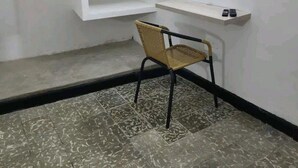 Une pièce avec une chaise, une petite étagère et un escalier.