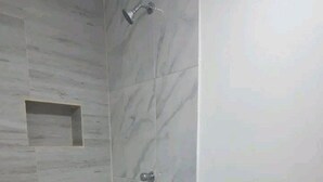 Une salle de bain moderne équipée d’une douche, de toilettes et d’une petite étagère.