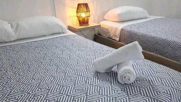 Une chambre d’hôtel avec deux lits, chacun agrémenté de draps à motifs et d’une table de chevet avec une lampe.