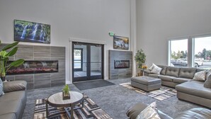 A modern living room with a fireplace, comfortable seating, and large windows.