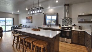 A modern kitchen with a large island, dark wood cabinets, stainless steel appliances, and a view of the outdoors.
