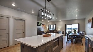 A modern kitchen with a central island, wooden cabinets, and a dining area with a table and chairs.