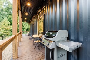 Un espace extérieur abrité comprenant un barbecue, une terrasse en bois et des sièges.
