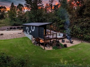 Une cabane moderne dotée d’une terrasse, d’un espace salon extérieur et d’un foyer.