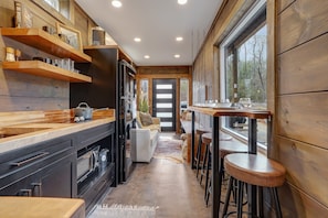 Enjoy cooking in this well-equipped kitchen with a central island, sink, and stove, leading to a dining area with a bar counter and stools.