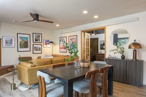 A modern living room with a sofa, dining table, and chairs. There are framed pictures on the wall, a ceiling fan, and a cabinet with a mirror. - 2BD/2BA w/ Hot Tub + Sauna + Free Vail Beaver Creek Shuttle (Avon)