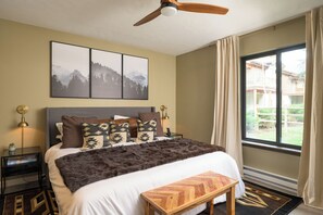 A bedroom with a large bed, a ceiling fan, a window with curtains, and two framed pictures on the wall. - 2BD/2BA w/ Hot Tub + Sauna + Free Vail Beaver Creek Shuttle (Avon)