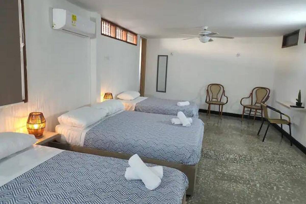 A hotel room with two beds, a ceiling fan, a desk, and two chairs.