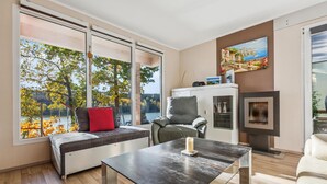 A modern living room with a large window, a sofa, a table, and a fireplace.