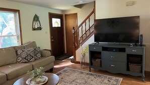 A living room with a sofa, a coffee table, a TV, and a staircase.