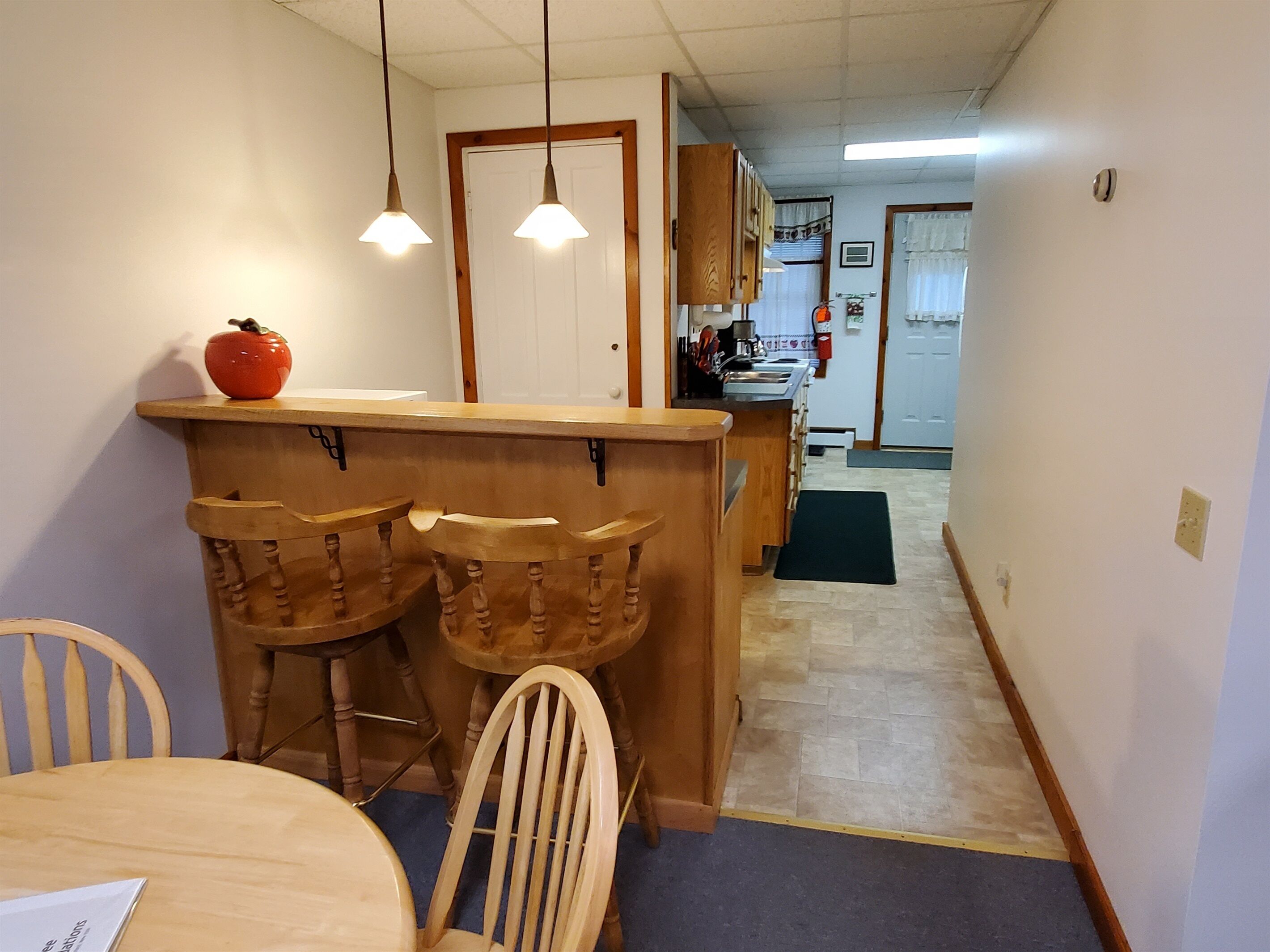 A kitchen area with a wooden counter, bar stools, and hanging pendant lights.
