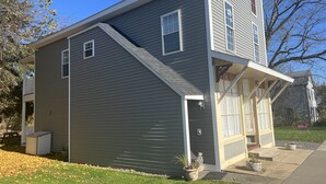 A two-story house with a grey exterior, a front porch, and a small attached garage. - Apple Tree Apt 2, Charming 2nd fl apt, under 5 minutes to Dreams Park (Milford)