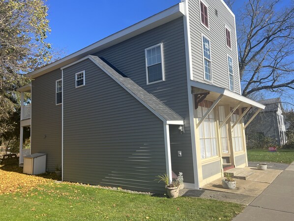 A two-story house with a grey exterior, a front porch, and a small attached garage.