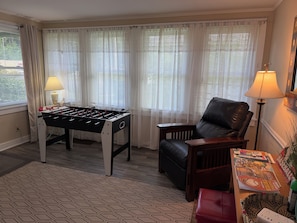 A room with a foosball table, a leather armchair, and a table with magazines.
