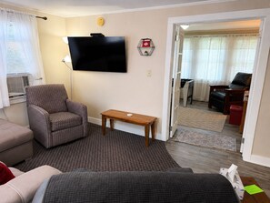 A living room with a flat-screen TV, a patterned armchair, a wooden coffee table, and a sofa. - Apple Tree Oneonta, Under 1 mile to ASV (Oneonta)