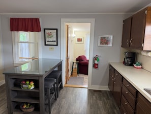 A kitchen with a dining area, a fire extinguisher, and a coffee maker. - Apple Tree Oneonta, Under 1 mile to ASV (Oneonta)