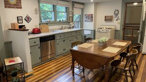 Une cuisine avec un plancher en bois, une table à manger avec des chaises, une cuisinière et un réfrigérateur.