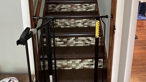 Uma escada com corrimão de madeira e guarda-corpo de metal, que leva a um andar superior.
