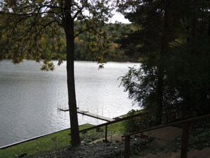 Enjoy a tranquil lakeside view from the deck, surrounded by lush greenery and trees.