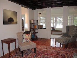 Relax in this inviting living room with a comfortable armchair, side table, and bookshelf filled with books and decorative items.