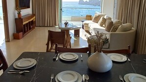 A dining area with a table set for four, a sofa, and a television in the background.