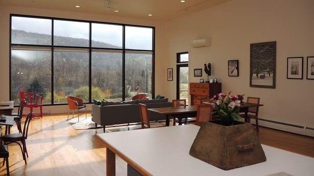 Une pièce spacieuse dotée de grandes fenêtres, d’une table en bois et de meubles modernes.