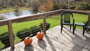 Une terrasse en bois avec une rambarde, deux citrouilles et une chaise.