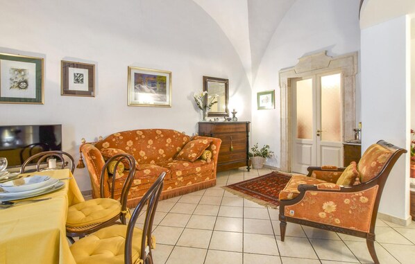 Un salon spacieux comprenant un canapé, des fauteuils, une table à manger et un téléviseur.