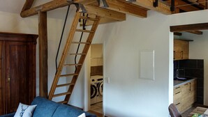 Ett vardagsrum med ett träpanelat tak, en blå soffa och ett träskåp.